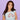 Woman wearing a light blue t-shirt with a colorful graphic design on a purple background