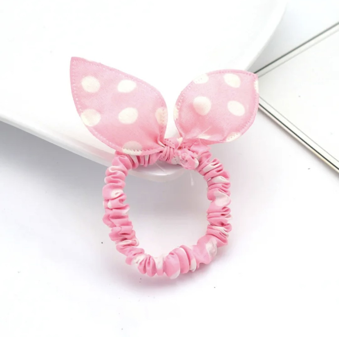 The image displays a delicate light pink bunny ear headband adorned with white polka dots. This accessory is perfect for giving your Hashie a playful and stylish look or for adding a touch of whimsy to your desk pets.