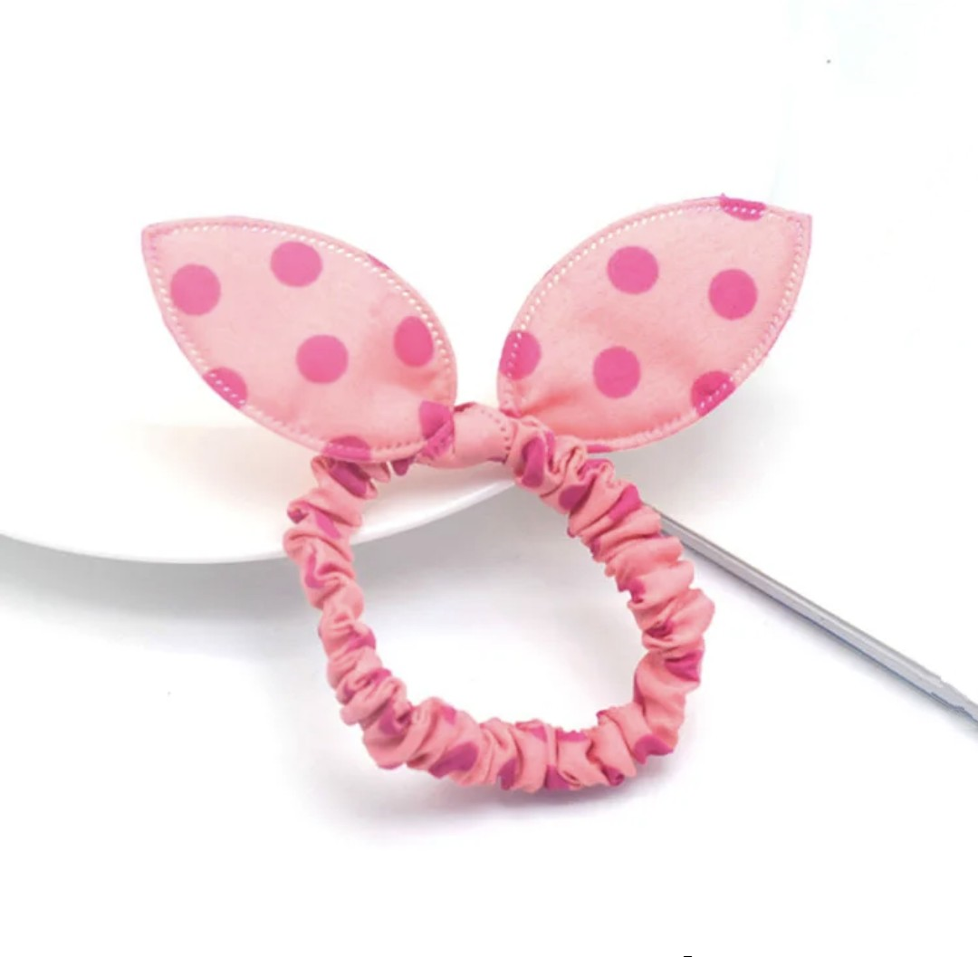 The image shows a soft pink bunny ear headband with darker pink polka dots, exuding sweetness and playfulness for Hashies or as a charming accessory for desk pets.