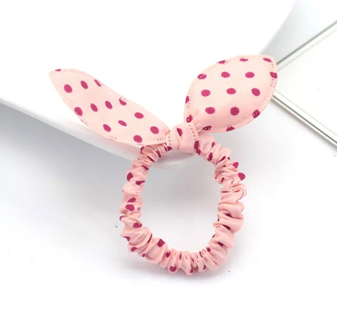 The image shows a charming light pink bunny ear headband adorned with dark pink polka dots, a delightful accessory for Hashies or as a sweet addition to desk pets.